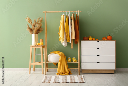 Interior of hallway with autumn clothes, drawers and pumpkins