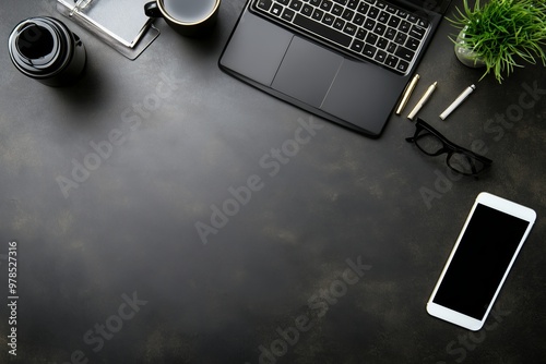 A neatly organized modern workspace featuring a laptop, smartphone, glasses, coffee, and stationery on a dark desk.