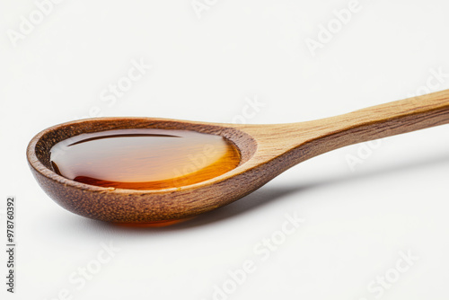 A wooden spoon with maple syrup or honey, isolated on a white background, studio shot.