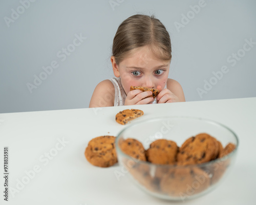 A little girl tries to steal cookies from the table. 