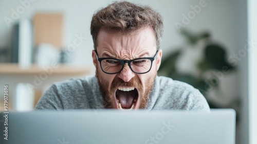 A mid adult businessman yelling intensely at his computer screen displaying deep and rage over a technology related issue or problem in his digital work life