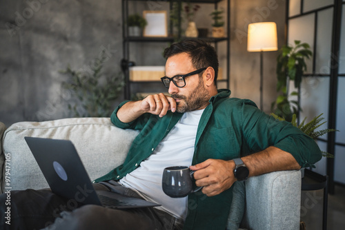 Adult man in green shirt work on laptop in cozy living room setting