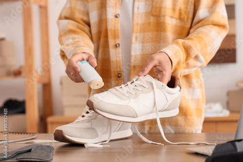 Male shoemaker polishing sneaker in repair shop, closeup