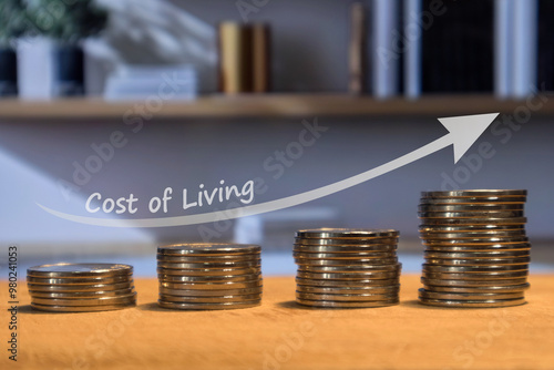 Coins stacked with the arrow up on a wooden table. Increasing of cost of living concept.