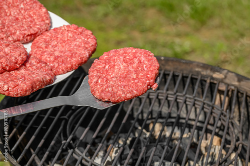 Szef kuchni wykłada burgery z surowego mięsa wieprzowego na rozgrzany ruszt na grillu, smażenie bez tłuszczowe, zdrowy fast food 