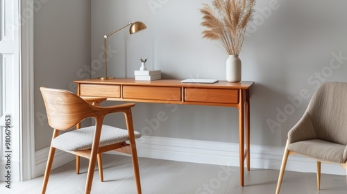 A stylish wooden desk with chair and decorative plant, creating a modern workspace in a minimalist setting.