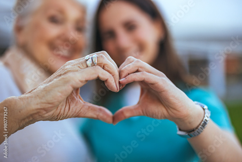 Elderly Woman and Caregiver Forming Heart Shape with Hands