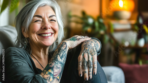 smiling elderly woman with gray hair and vibrant tattoos sitting comfortably indoors