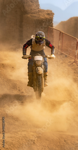 Motocross rider in action racing down a steep slope surrounded by dusty terrain in an endurance race.