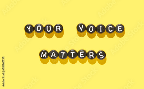 Inspiring quote your voice matters in black and white beads on vibrant yellow background for empowerment concept.