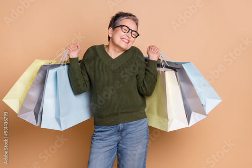 Photo of lovely positive cute senior woman wear green stylish clothes mall store isolated on beige color background