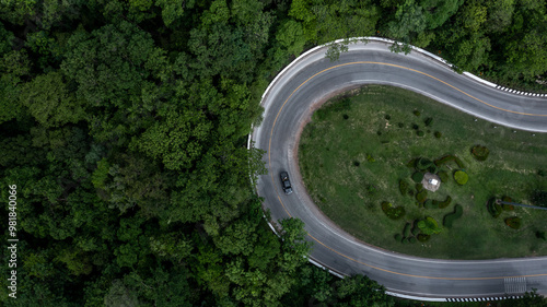 Aerial view car drive in green tree forest road winding road through the forest, Car drive on asphalt road between green tree forest, Electric vehicle EV car drive on asphalt road green tree forest.