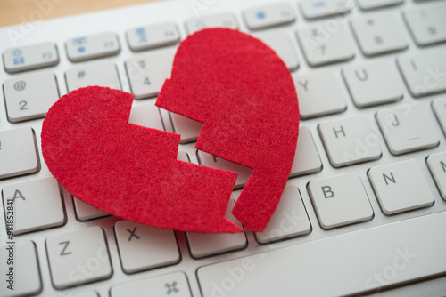 Red broken heart on white keyboard computer background. Online internet romance scam or swindler in website application dating concept. Love is bait or victim.