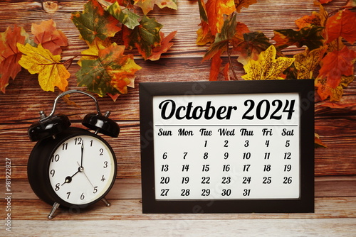 OCTOBER 2024 monthly calendar for planning and management concept with alarm clock on wooden background