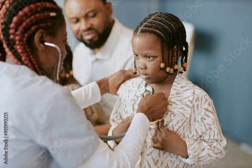 Child receiving medical examination with stethoscope by professional medical practitioner with other adults in background looking with concern