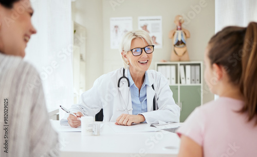 Checkup, doctor and talking to child, smile and mature woman with question, growth and development. Office, mom and daughter in appointment, writing and conversation for health of kid or pediatrician