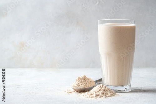 Healthy protein shake served in a tall glass alongside a scoop of protein powder on a light countertop