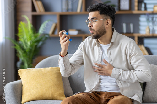 Man using inhaler while experiencing respiratory discomfort on sofa at home