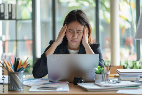 Work stress concept: Woman with headache at office