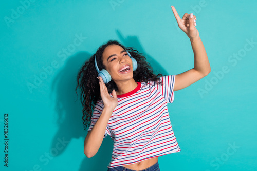 Photo portrait of lovely young lady enjoy music headphones dressed stylish striped garment isolated on cyan color background