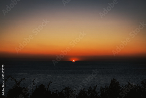 El último rayo de sol se despide en el horizonte, mientras el cielo y el mar se tiñen de tonos cálidos, creando un cuadro perfecto de serenidad y belleza.