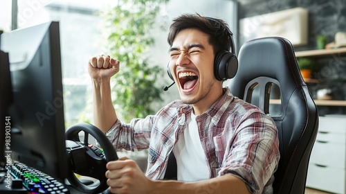 Asian male gamer playing an online car drive simulation game with a steering wheel controller. The gamer wins a sports game with the emotion of victory. Esport streaming game online.