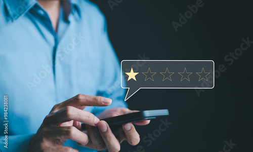 Negative customer review concept. A person use smartphone to give a one-star rating, symbolizing customer dissatisfaction, negative feedback, and online reviews in business reputation. 1 star score,