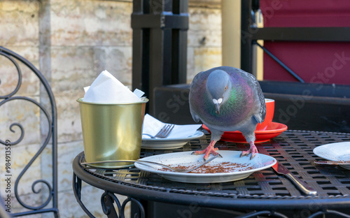 Pigeon pecks crumbs on the table of an outdoor cafe.