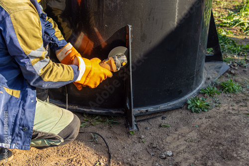 Worker in uniform saws off with a grinder. Plastic sawing. Compact circular saw