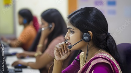 A young woman wearing a headset works at a desk in an office.