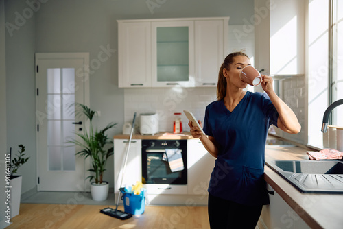 Young woman enjoying in cup of coffee after cleaning her home.