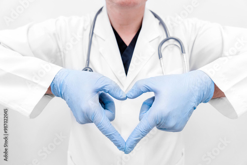 A doctor making a heart with his hands Doctor with a stethoscope in a medical mask and gloves makes a heart symbol with his hands. Cardiological concept. Love and a healthy heart.