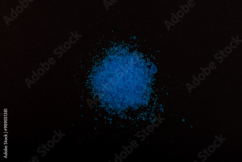 Pile of Cupric sulfate on dark surface, top view. Blue vitriol or bluestone. Bright blue crystal powder. In agriculture, copper sulfate used as antiseptic, fungicide and fertilizer