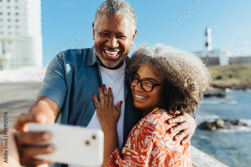 Retired happy pair taking a selfie on vacation by the ocean in Bahia