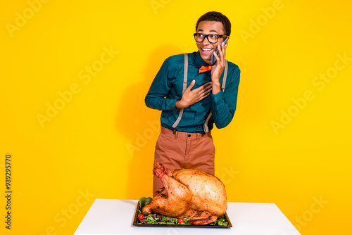 Portrait of elegant young man speak telephone roasted thanksgiving day turkey isolated on yellow color background