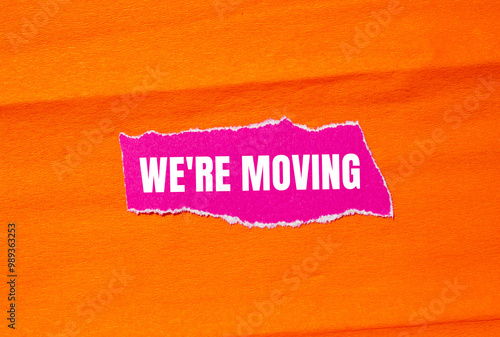 We are moving message written on ripped torn pink paper with orange background. Conceptual we are moving symbol. Copy space.