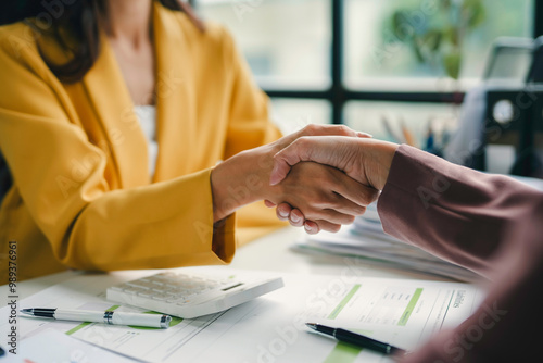 Businesswomen shaking hands after reaching an agreement on a deal during a meeting at the office