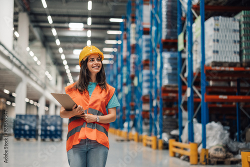 Woman warehouse inspector smiling with clipboard under bright lights