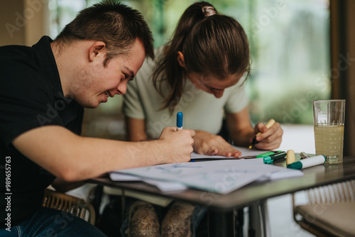 A joyful moment with young friends, including a male with Down syndrome and a girl in a wheelchair, drawing and painting together at a table.