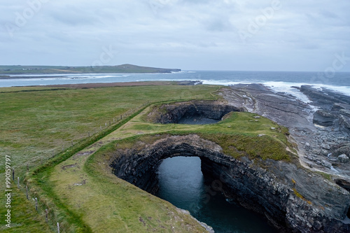 Aerial shot of the natural stone bridge known as the Bridges of Ross, dramatically perched on the rugged coast of Kilkee, Ireland