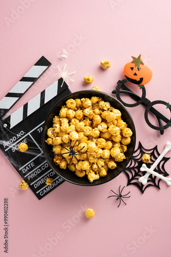 Bowl of popcorn with Halloween vertical themed decorations including a clapperboard, toy spiders, pumpkin glasses, and skeleton bones