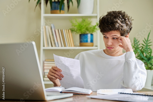 Serious young guy reading letter, paper document