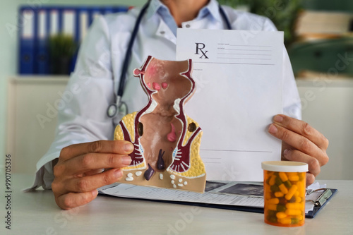 Proctologist holds pills and an artificial model of the human rectum. Drugs are used for rectal diseases. Treatment of rectal inflammation