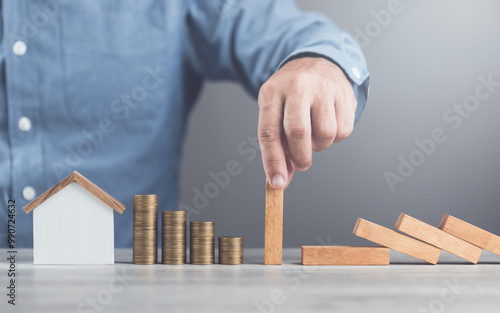 Businessman uses his hand to stop wooden blocks from falling, symbolizing the protection of assets and strategic decision-making in managing resources effectively, domino effect and risk management