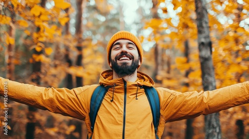 Man standing in a forest, arms open wide, smiling, side light, autumn colors