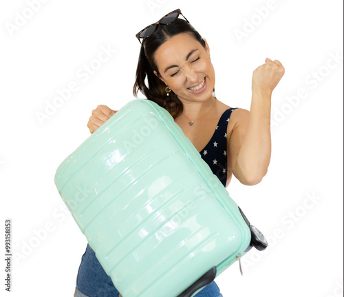 Young traveler woman holding a suitcase raising fist after a victory, winner concept. isolated over transparent background