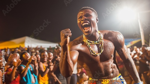 Togolese Man Engaged in Traditional Wrestling Match at Evala Festival Amid Cheering Crowd and Bright Outdoor Lighting