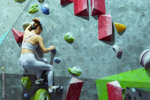 Asian sportswoman practices an indoor rock climbing wall.