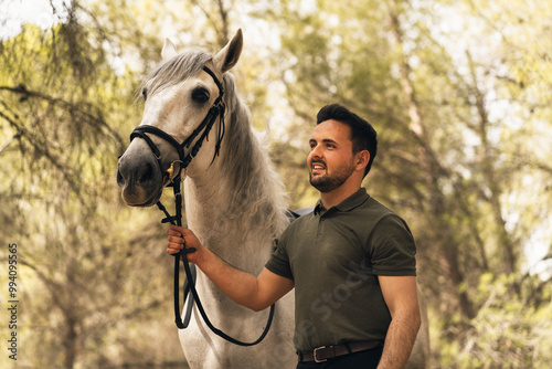 Portrait of a man and his horse posing facing left while the man leads the horse on foot. Riding school concept.