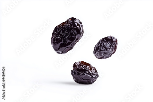 Falling prunes captured in mid-air, showcasing their rich texture against a bright white backdrop